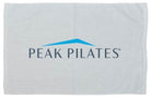 A white towel featuring the blue and gray Peak Pilates logo printed in the center.