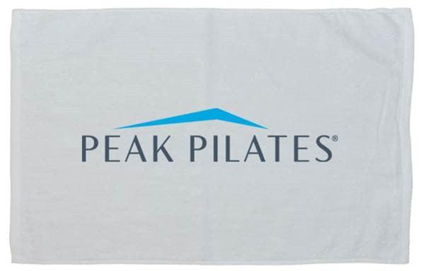 A white towel featuring the blue and gray Peak Pilates logo printed in the center.